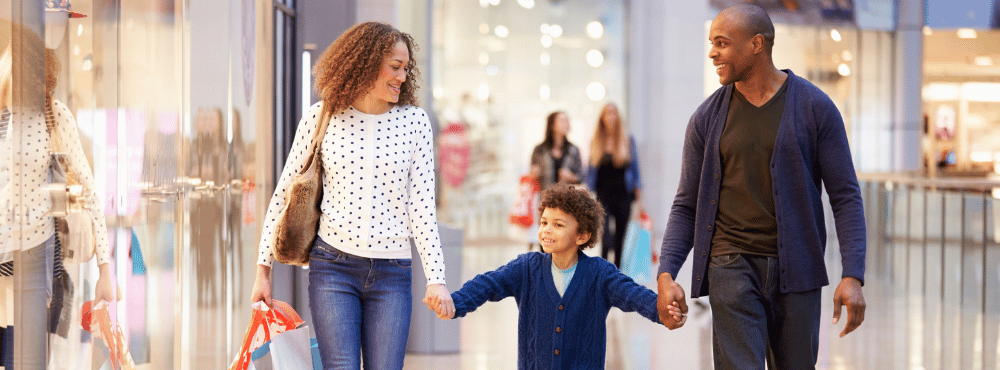 Couple with a child having a lovely stroll though a nicely lit shopping centre