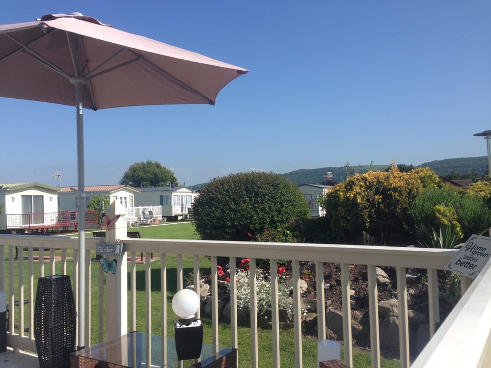 Decking with a parasol outside one of the caravans at Pentre Mawr Caravan Park