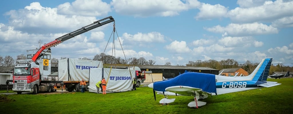 The TF Jackson team carefully unload modular buildings next to a small grounded aeroplane