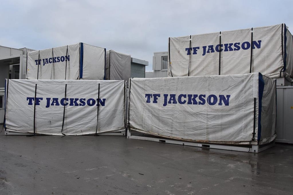 TF Jackson-branded covers on modular units at an industrial facility, indicating storage or transport preparation