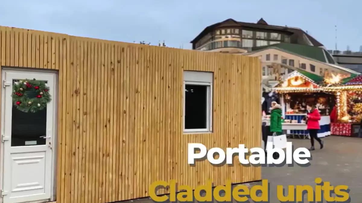 Timber-clad portable building with a festive wreath on the door, located at a Christmas market.