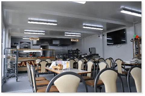 Canteen with multiple tables, chairs, and a food service area