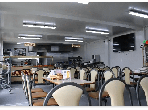 Canteen with multiple tables, chairs, and a food service area