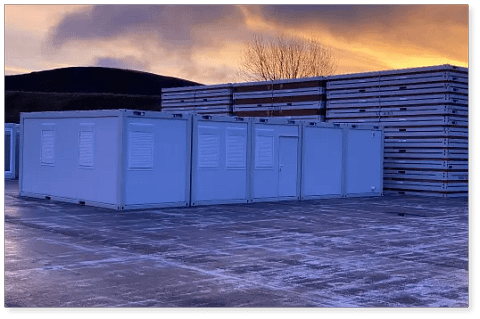 Storage containers lined up in an outdoor lot at dusk