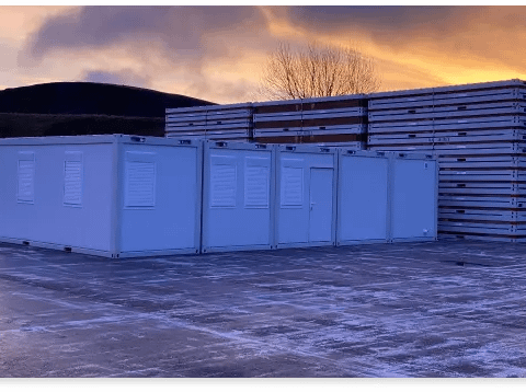 Storage containers lined up in an outdoor lot at dusk