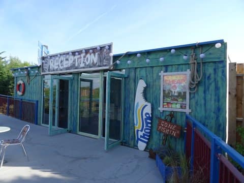 Creatively decorated modular building with a "Reception" sign, featuring artistic marine-themed paintwork and hanging decorations