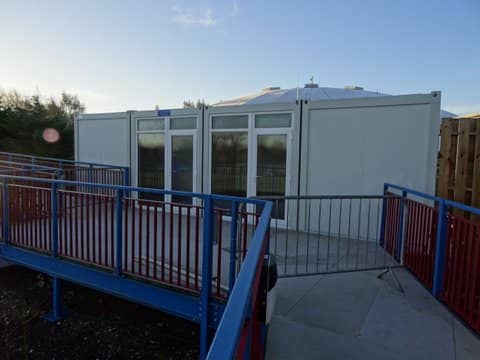 Creatively decorated modular building with a "Reception" sign, featuring artistic marine-themed paintwork and hanging decorations