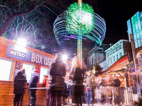 Vibrant night scene at Udderbelly Festival with lit-up attractions and bustling crowd