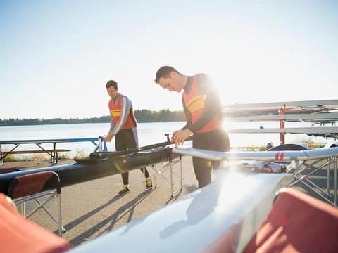 Rowers preparing sculls at waterfront