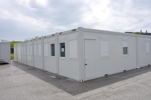 A row of white modular buildings with shutters on the windows.