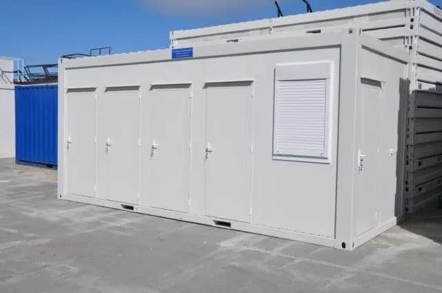 Exterior of a white modular building with shuttered windows and multiple doors