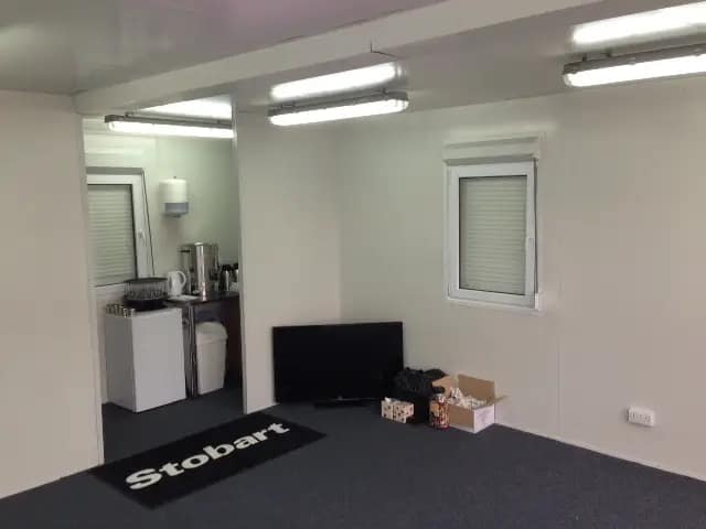 Interior of a modular office with kitchen amenities and a "Stobart" doormat.