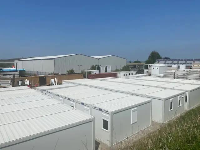 Disassembled modular building frames stacked beside a road.