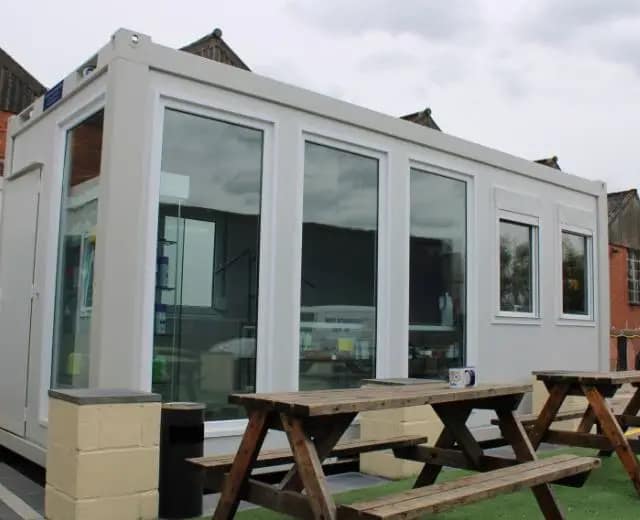 Small modular building with picnic tables outside.