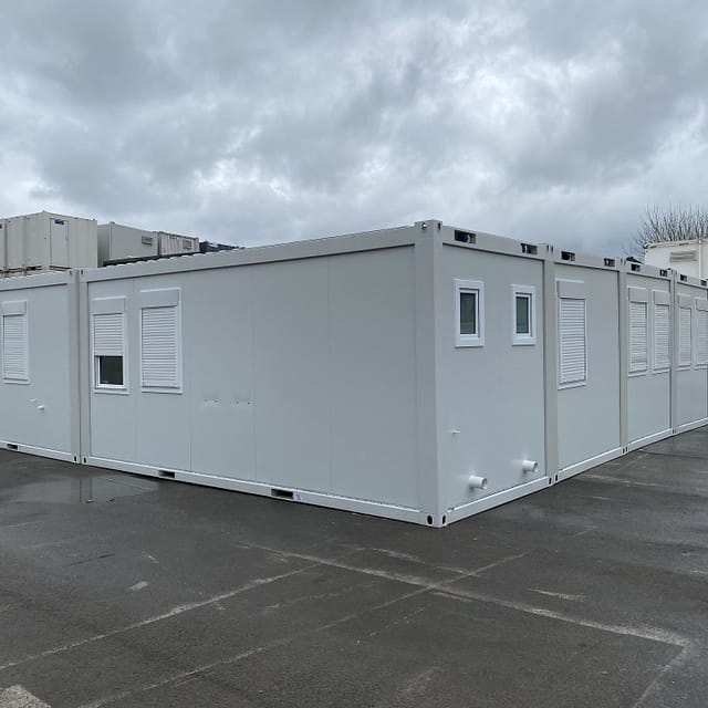 Large modular unit with shuttered windows and exterior doors, situated in a commercial area