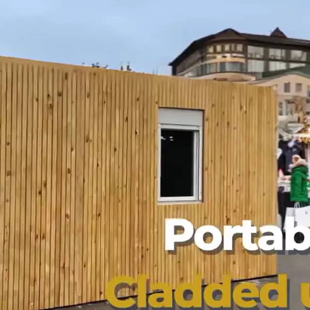 Timber-clad portable building with a festive wreath on the door, located at a Christmas market.
