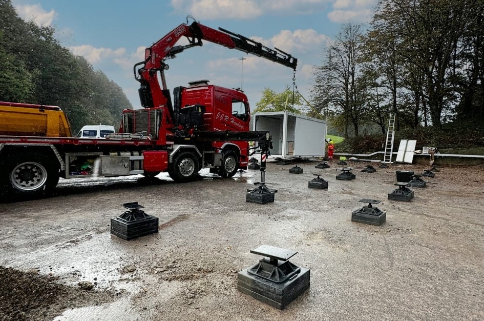Truck craning a TF Jackson prefabricated building shell into place on portable foundations