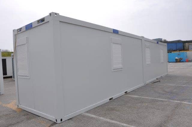 Corner perspective of a similar white modular building in a parking area.