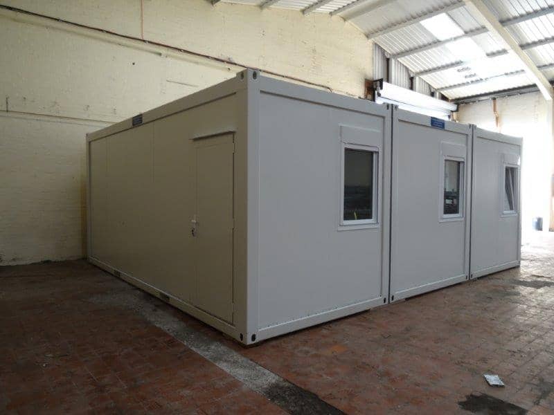 Exterior view of a modular building set inside a warehouse with large doors and windows